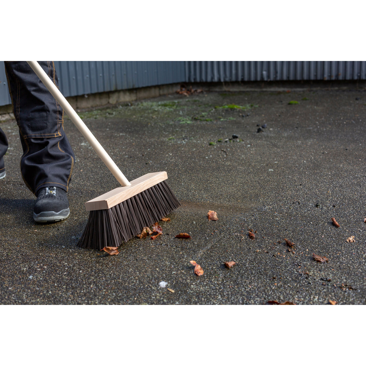 Skaft uden gevind i træ, Ø2,5cm, 150cm, med gadekost på en udeplads.