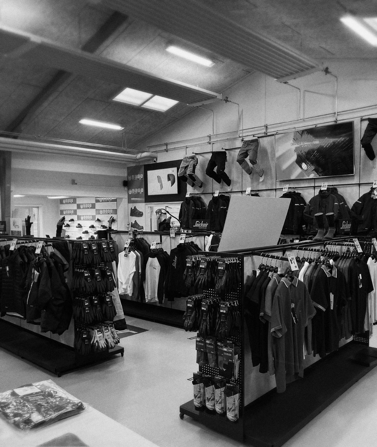 Indvendig butik med arbejdstøj, handsker og fodtøj udstillet på stativer og vægge